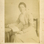 Amey Cook sitting on a chair with an open book on nearby table.