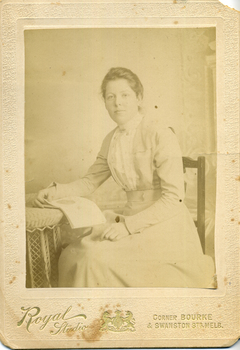 Amey Cook sitting on a chair with an open book on nearby table.