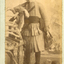 Young dark haired female child wearing a pleated suit with short skirt and cummerbund,