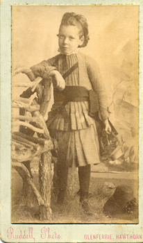 Young dark haired female child wearing a pleated suit with short skirt and cummerbund,