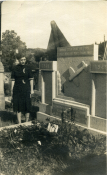 Woman in a dark dress standing next to a tombstone 