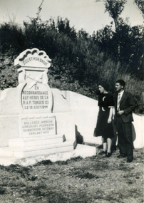 Man and woman in war cemetery looking at headstone , dated 1944. 