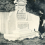 white tombstone with a patterned curved top with carved aero plane on front with a French inscription. 