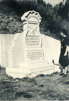 white tombstone with a patterned curved top with carved aero plane on front with a French inscription. 