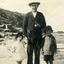 Sydney Till between Alwyn & Alison (his children) standing on a rocky beach. 