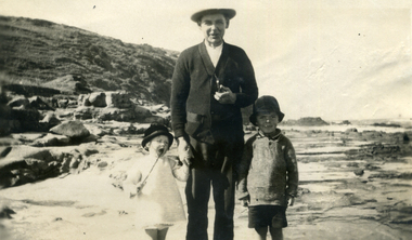 Sydney Till between Alwyn & Alison (his children) standing on a rocky beach. 