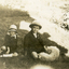Two children sitting on a lawn with a dog.