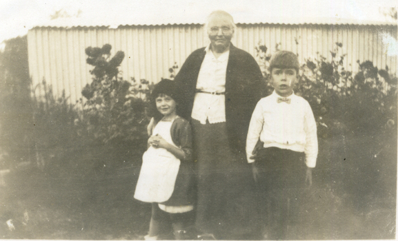 An elderly woman wearing a white blouse and dark jacket and skirt. 