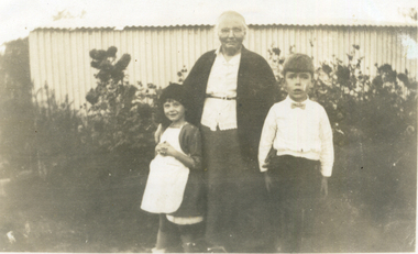 An elderly woman wearing a white blouse and dark jacket and skirt. 