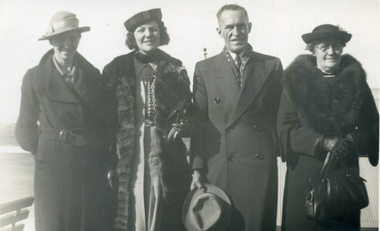 Four adults, three women and one man, standing in a row, 