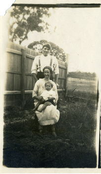 Stanley Till standing behind Evelyn Till who is seated with Alwyn Till on her knee. 
