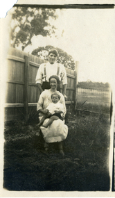 Stanley Till standing behind Evelyn Till who is seated with Alwyn Till on her knee. 