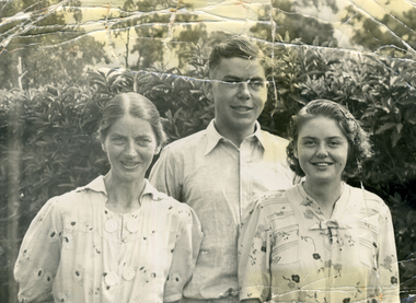 Evelyn, Alwyn and Alison Till standing in front of a hedge.