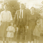 Till family group of three adults and two children standing in front of a wooden fence.