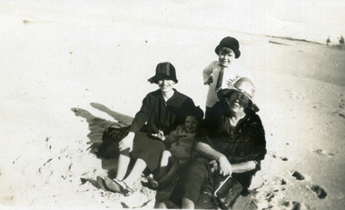Two women and two children on a beach. 