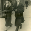 Street scene of three people. Facing the camera, two people wearing winter clothes.