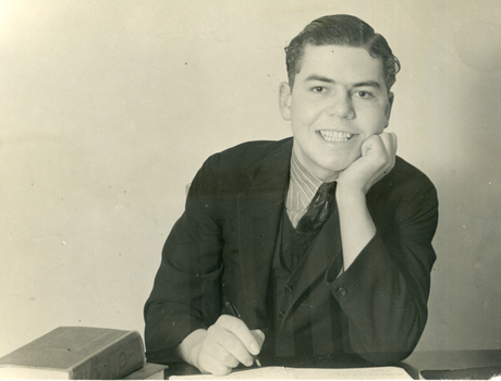 Alwyn Till sitting at a desk with pen in hand.
