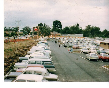 Photograph of cars parked along Springfield Road and in the car park of the Old Orchard Shopping Centre. 