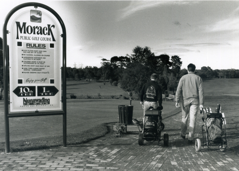 Morak Public Golf Course, Vermont South. Large sign on left and two golfers heading out on right. 1994