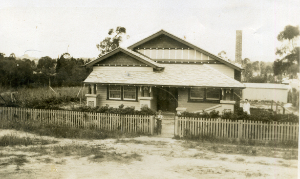 Till house in Clive Street, Mitcham. Picket fence, unmade road and a small boy at the gate.
