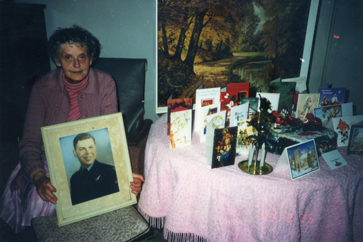 Alison Till holding a photograph of her brother Alwyn in airforce uniform. 