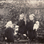 Three Lowen children outside in the garden, one on a hobby horse. 