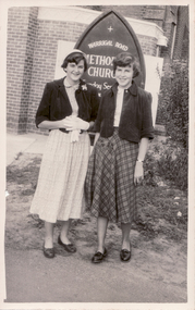 Black and white photograph of two young women standing in front of the Warrigal Road Methodist Church about 1954. .