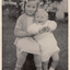  Gloria Mullens seated in a yard and holding her brother.