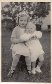  Gloria Mullens seated in a yard and holding her brother.