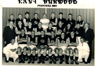 Black and white studio portrait of the East Burwood Football Club in 1964. The photo has the title 'East Burwood Premiers 1964'