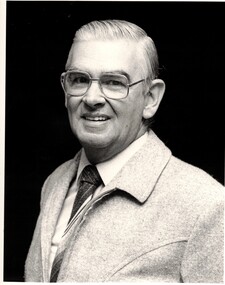 Black and white photograph. of .Ken Paxton in 1984 wearing glasses, and collar and tie. 