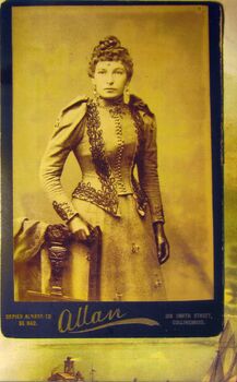 sepia photograph of a lady in a tight fitting suit .