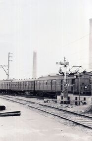 An early black and white photograph of a passenger train heading West towards the city