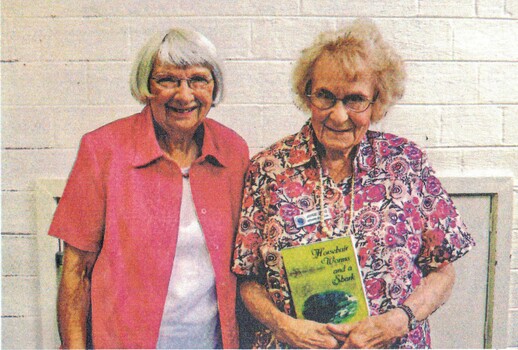 Coloured photo of Valda Arrowsmith and Joyce Suto who is holding a book of her family history and original poems.