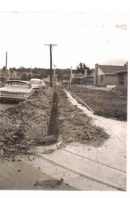 Black & white photograph of a trench dug in preparation for laying gas pipes in Aubrey Street Mitcham.