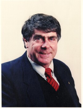  Bill Bowie. Wearing a dark suit with a black and red stripped tie.
