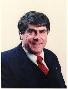  Bill Bowie. Wearing a dark suit with a black and red stripped tie.
