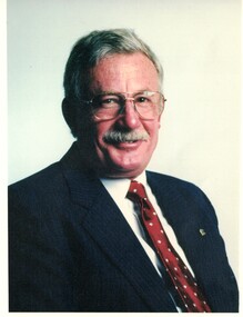 David McKittrick. Wearing a dark suit with a burgundy tie with yellow dots.