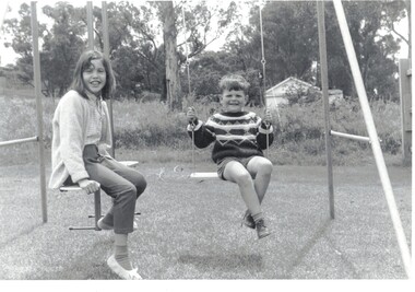 2 Children on a swing in back yard of 27 Good Governs Rd Mitcham.
