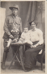 Photograph showing Lesley Hogan in uniform standing behind Leslie Jnr, with Frances seated and holding Edna.