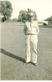 Black & White photograph of a man standing on a grassed area and wearing a uniform.