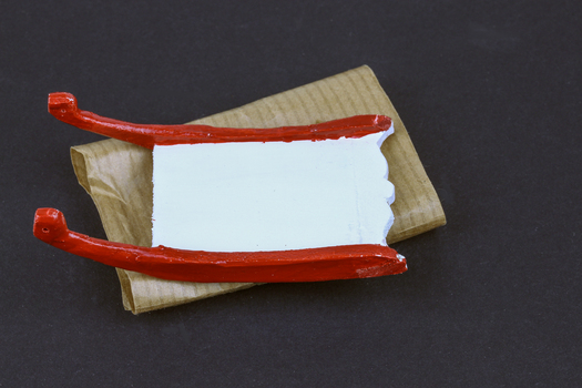 white and red painted wooden sledge wrapped in brown paper
