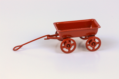 four-wheeled red painted metal wagon with shaft