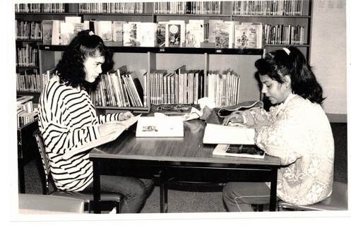 Black and white photograph showing two girls reading.