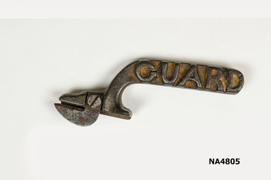 A metal bottle or tin opener with a round handle and the name "Guard" stamped on 