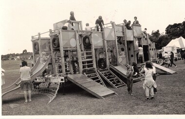 Black and white photograph of children on  playground equipment.