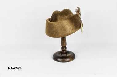 Small light brown felt hat with brown and fawn curled feather on one side.