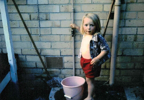 Kelly Gardiner in backyard playing with tap and bucket