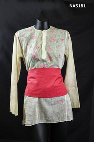 Embroidered cotton blouse with red cummerbund.