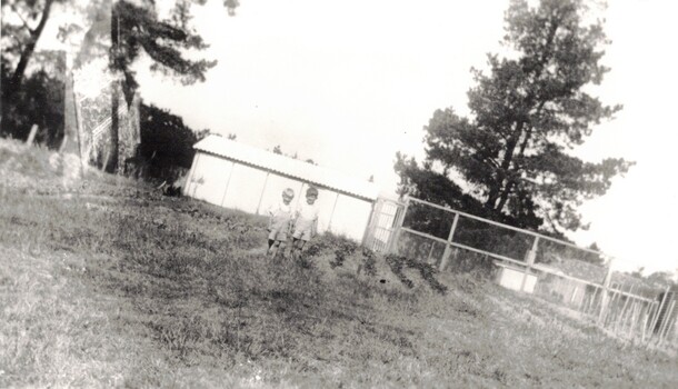 Two boys standing outside a shed